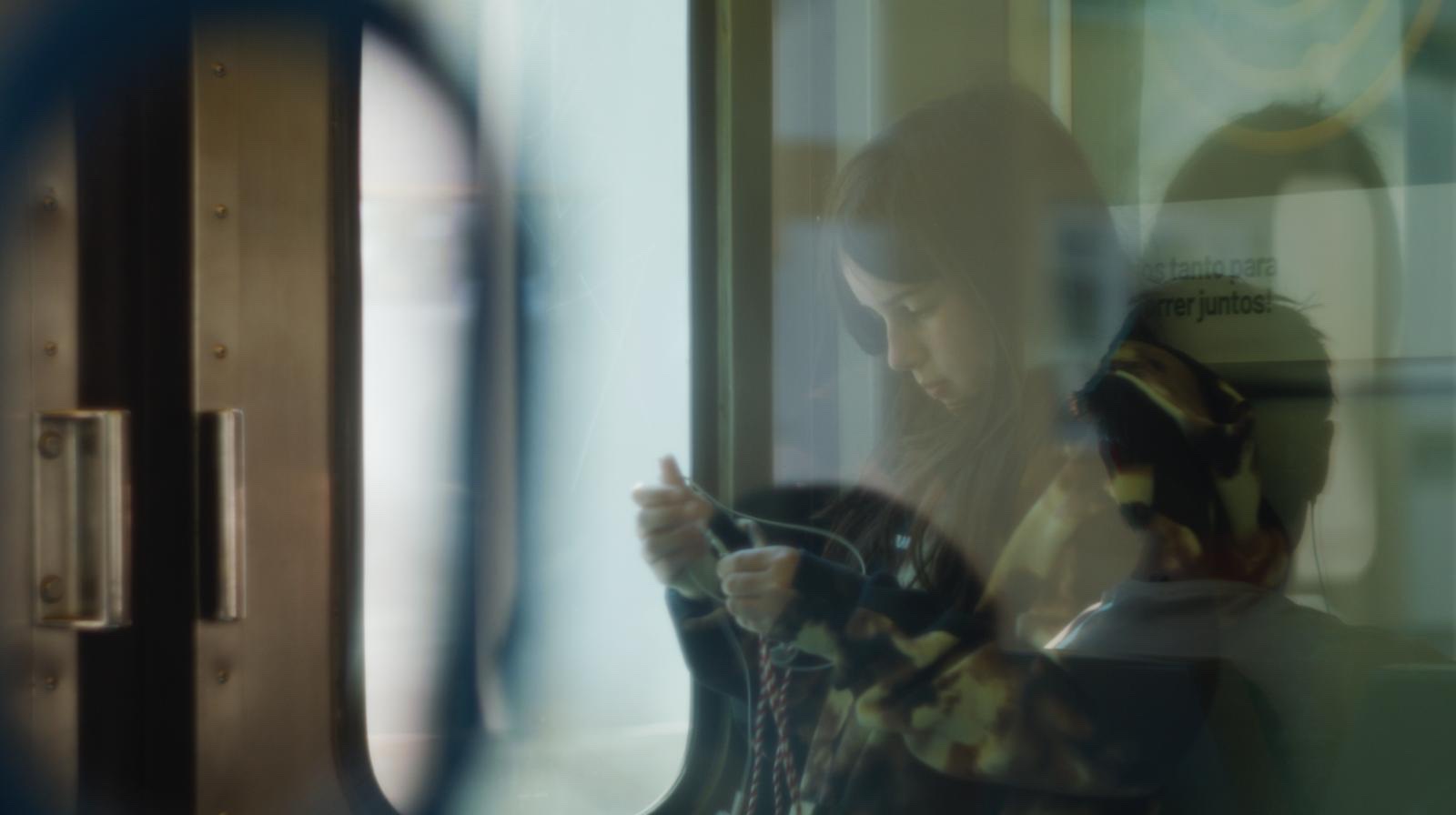 Still from It's Her — a girl on a train, seen through the carriage window